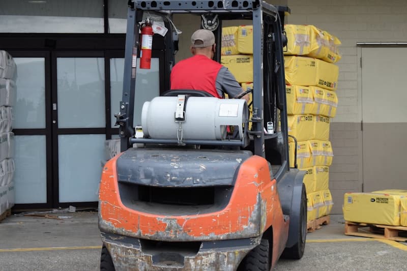 Forklift operator moving pallets in a warehouse